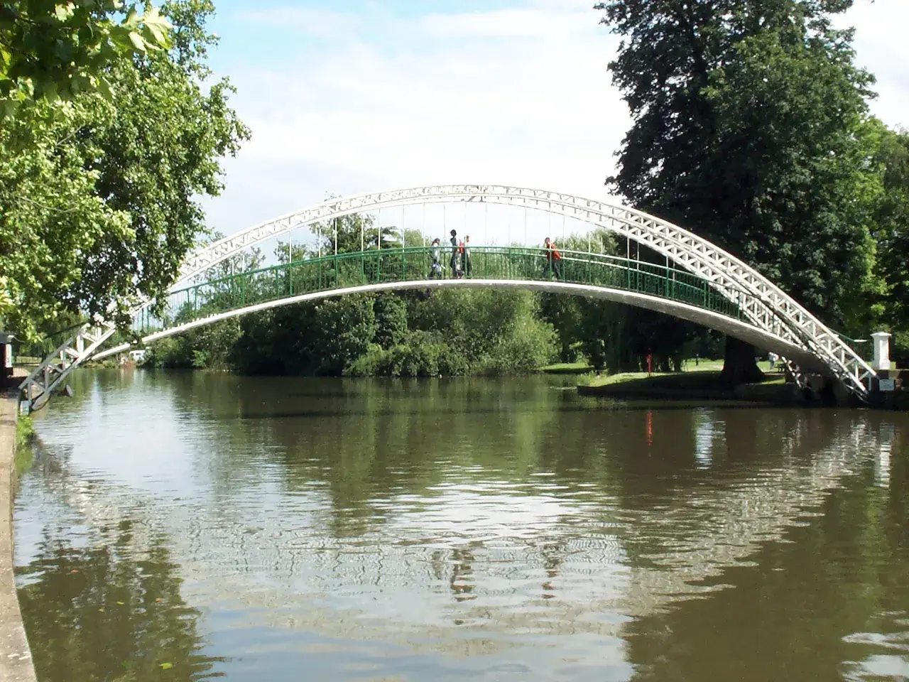 The white arched suspension footbridge over the river in Bedford, framed by trees